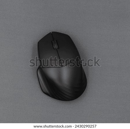 Black computer mouse on a gray background.