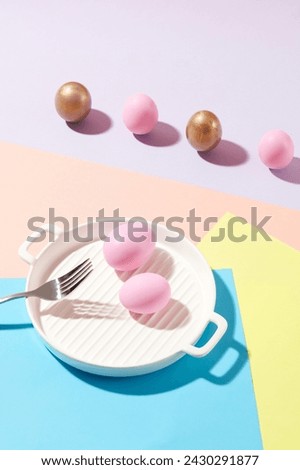 Ceramic dish in pan-shaped featured two pink eggs and a fork. Golden and pink Easter eggs are arranged in a line. Easter is one of the principal holidays, or feasts, of Christianity