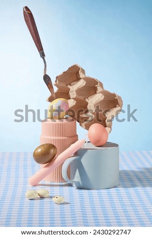 On light blue background and checkered plain, Easter eggs and Easter candle decorated with ceramic cups. Creative advertising photo. Front view