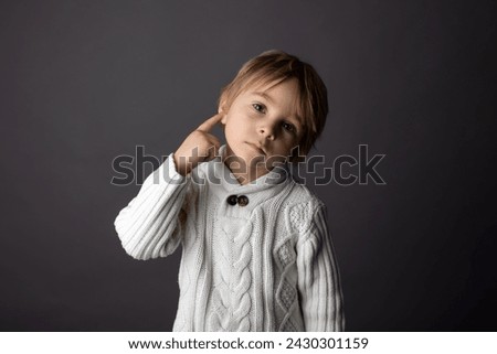 Cute little toddler boy, showing DEAF gesture in sign language on gray background, isolated image, child showing hand sings for deaf people