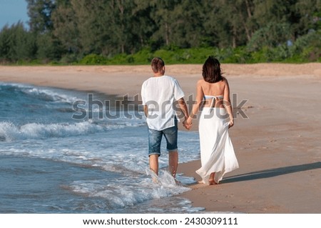 Honeymoon at the sea. Back view of loving couple walking away at sandy beach