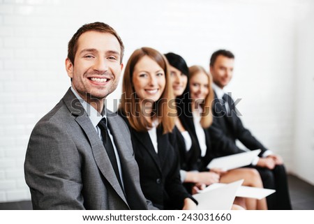 Confident businessman sitting with business partners in background