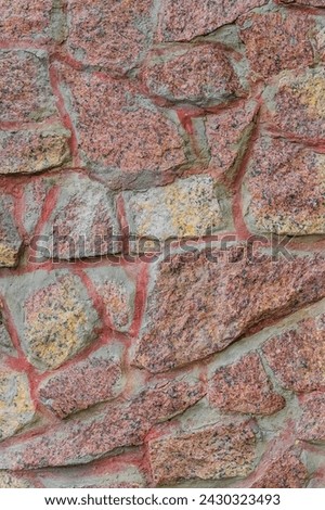 It's close up view of red and yellow stones of wall. This is photo of pink stone wall of the building. It is view of  stone wall of castle. It is view of stone wall texture.