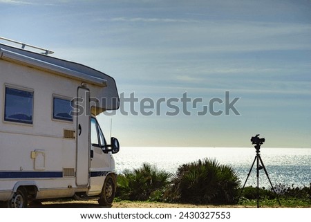 Camera on tripod and caravan rv camping on mediterranean coast beach in Spain. Vacation in mobile home, travel pictures.