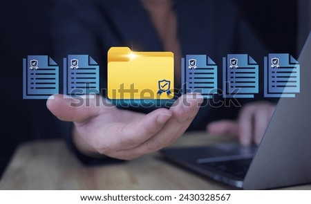 Businessman holds folder icon with shield on virtual screen for accessing confidential documents, document management and online file storage, personal data and corporate privacy protection.
