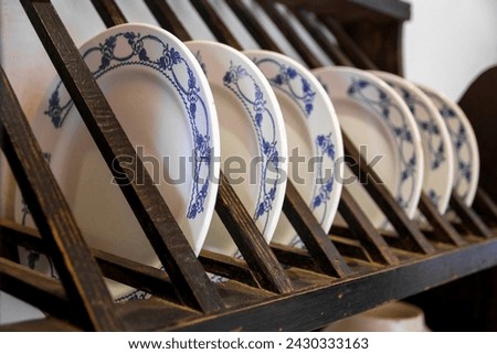 Set of plates with blue ornamental designs, neatly arranged in a wooden plate rack in a traditional kitchen Royalty-Free Stock Photo #2430333163