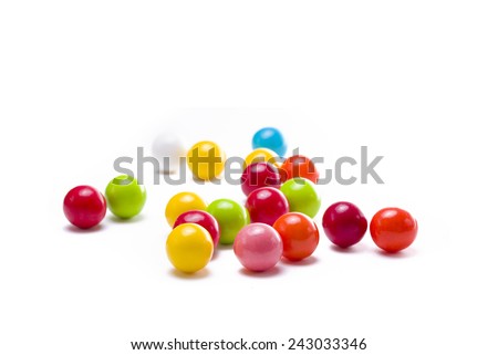 Multicolored gumballs sitting in a white background Royalty-Free Stock Photo #243033346
