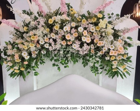 Colorful fake flowers to decorate the aisle.  Curved floral decorations extend over the wedding chairs.  Soft focus. Royalty-Free Stock Photo #2430342781