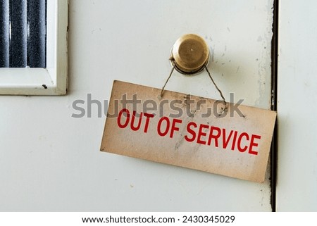 A retro sign hanging in front of an elevator door that says the elevator is out of service