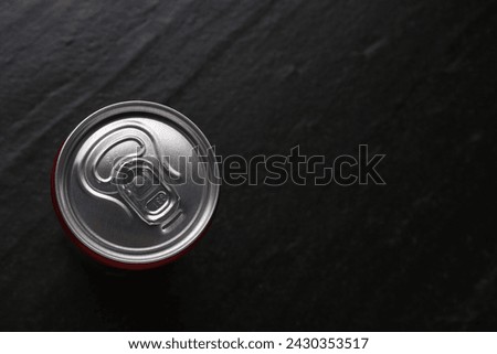 Energy drink in can on black textured background, top view. Space for text