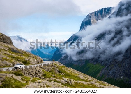 Car driving along the road at Trollveggen Norway with clouds around the mountains. High quality photo Royalty-Free Stock Photo #2430364027