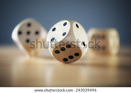 Rolling three dice on a wooden desk Royalty-Free Stock Photo #243039496