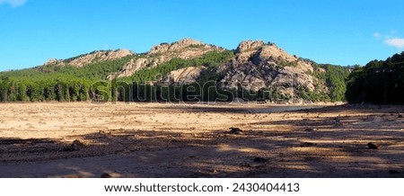 Near Porto-Vecchio, in the heart of Alta Rocca, Lake U Spidali is nestled between road and mountains. Due to the drought, the water level has dropped, revealing tree stumps cut before impoundment Royalty-Free Stock Photo #2430404413