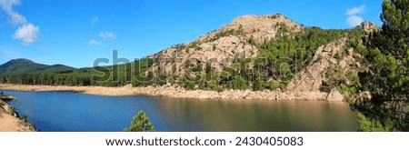 Near Porto-Vecchio, in the heart of Alta Rocca, Lake U Spidali is nestled between road and mountains. Due to the drought, the water level has dropped, revealing tree stumps cut before impoundment Royalty-Free Stock Photo #2430405083
