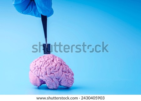 A hand in a medical glove inserts a flash card into a person's brain using tweezers