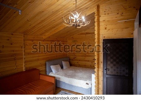 The cabins interior is paneled with wood and furnished with a bed, sofa, and armoire. A bearskin rug adds a touch of warmth to the space. Royalty-Free Stock Photo #2430410293