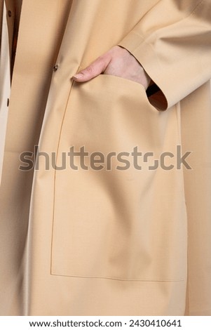 A model wearing an elegant beige coat with large front pockets. The coat is perfect for staying warm and stylish in the fall and winter. Royalty-Free Stock Photo #2430410641