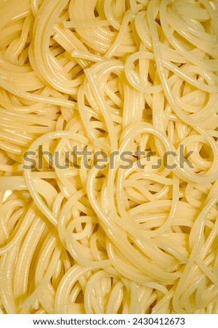 A close-up view of a plate of spaghetti. The spaghetti is a bright yellow color, The sheen from the oil adds to the chewy feel of the pasta.
