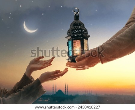 Ornamental Arabic lantern with burning candle glowing in hand. Festive greeting card, invitation for Muslim holy month Ramadan Kareem. Royalty-Free Stock Photo #2430418227