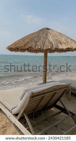 view of lounge chairs on the beach with straw umbrellas during the day