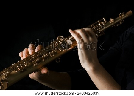 soprano saxophone in hands on a black background Royalty-Free Stock Photo #2430425039