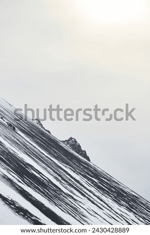 Abstract northen landscapes: Diagonal snow patterns adorn the slopes of Hafnarfjall mountain near Borgarnes against a grey sky (region of Vesturland, Iceland)
