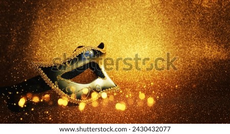 Photo of elegant Venetian mask over glitter gold background