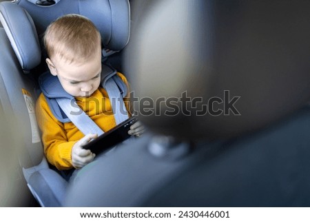 Little boy using smart phone in car interior while traveling. Childhood and technology concepts.
