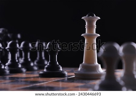 Close-up. The black pawn stands opposite the white queen. among chess pieces on a dark background