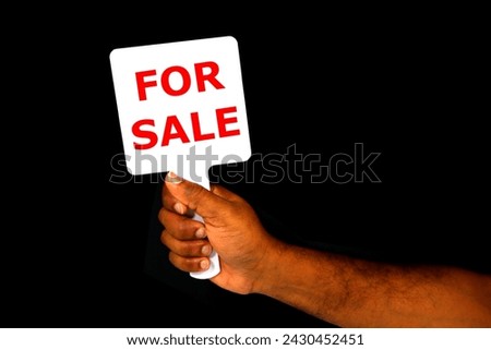 FOR SALE notice board holding hand with black background close-up view, Sale concept photography, Human hand held sign board 