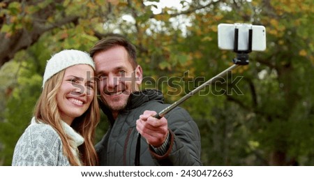 Image of emoji icons flying up with a young Caucasian couple taking a selfie with a selfie stick in a park in the background 4k