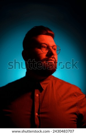 Evocative side profile of a man, his face illuminated in warm light against a contrasting cool blue background Royalty-Free Stock Photo #2430483707