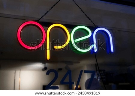 a brightly colored OPEN sign hangs on the window of a clothing store in the evening