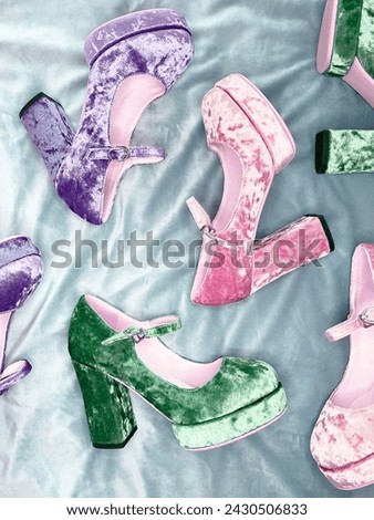 fashionable designer velvet boots in violet, pink and green colors, laid out in the store on a purple background