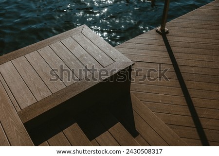 Top down photo of a part of a dock with water in the background. Steps have shadow.
