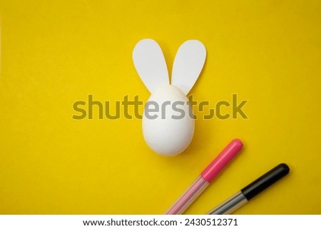 Food photo. Happy Easter. Chicken egg with rabbit ears and pink and black felt-tip pens on yellow background. Blank for coloring for children. Coloring book for kids. Greeting card. Copyspace. Gift