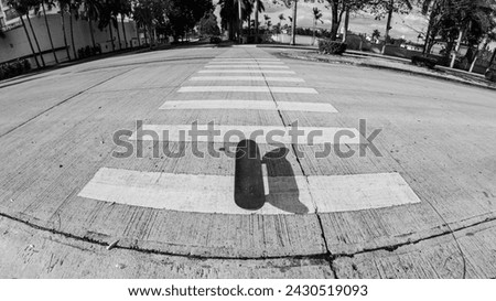 bnw black and white horizontal photo of a skateboard laying symmetric in the street on the crossing zebra with an extreme wide angle fish eye lens