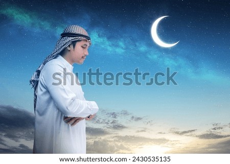 A Muslim man with agal in a praying position (salat) with a night scene background. Muslim concept Royalty-Free Stock Photo #2430535135