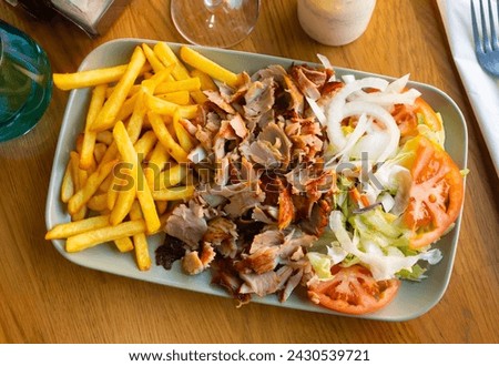 Dish with appetizing assorty of Armenian cuisine of delicious shish kebab, french fries, baked vegetables, fresh tomatoes Royalty-Free Stock Photo #2430539721