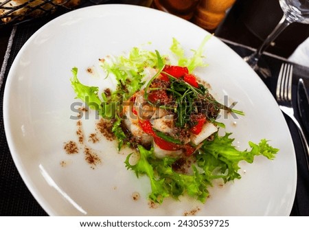 Appetizing cod timbale with baked red pepper garnished with rocket and olive tapenade ..
