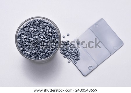 pearl silver masterbatch granules on a white background, with color chips as an example of the color produced, this polymer is a product colorant for products in the plastics industry Royalty-Free Stock Photo #2430543659