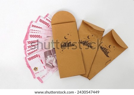 Close-up view THR envelope filled with Indonesian Rupiah banknotes. THR or Tunjangan Hari Raya is a holiday allowance or bonus traditionally given to employees and those in need near during Ramadan Royalty-Free Stock Photo #2430547449
