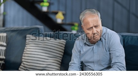Worried retired old elder senior man sitting alone on sofa couch feel sorrow anxiety at home. Unhappy Indian middle aged male grieving think lonely depressed pensive suffering health issue problems Royalty-Free Stock Photo #2430556305