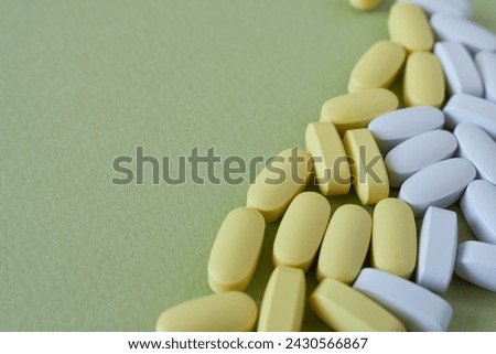 Close up of white and yellow pills on green background with copy space Royalty-Free Stock Photo #2430566867