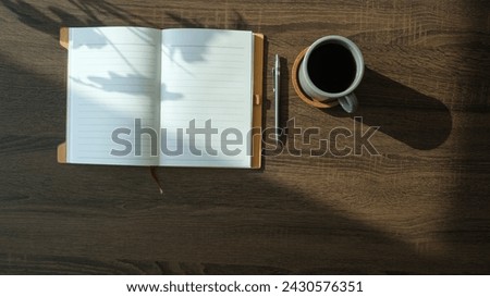 Flat lay notebook, coffee cup and potted plant on wood office desk.