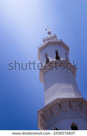 mosque tower with blue sky background with light shining on it
