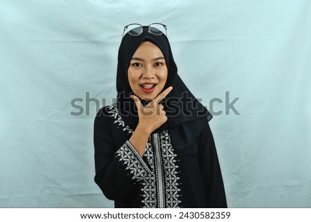 Asian Muslim woman wearing hijab, glasses and black dress with white pattern making chis gesture with a satisfied expression isolated on white background Royalty-Free Stock Photo #2430582359