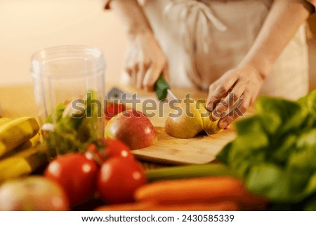 Cropped picture of female's hands cutting apple in kitchen on cutting board.