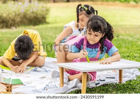 A little boy and girl were having fun drawing pictures, Group of children playing and on sunny summer day in the park,  holiday relaxation concept, picnic in summer park, outdoor education concepts