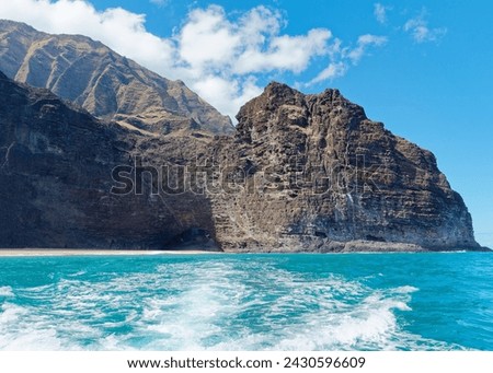 View from a tourist boat of an amazing cliff with cave entrance in the Pacific ocean at Napali Coast, Island of Kauai, Hawaii